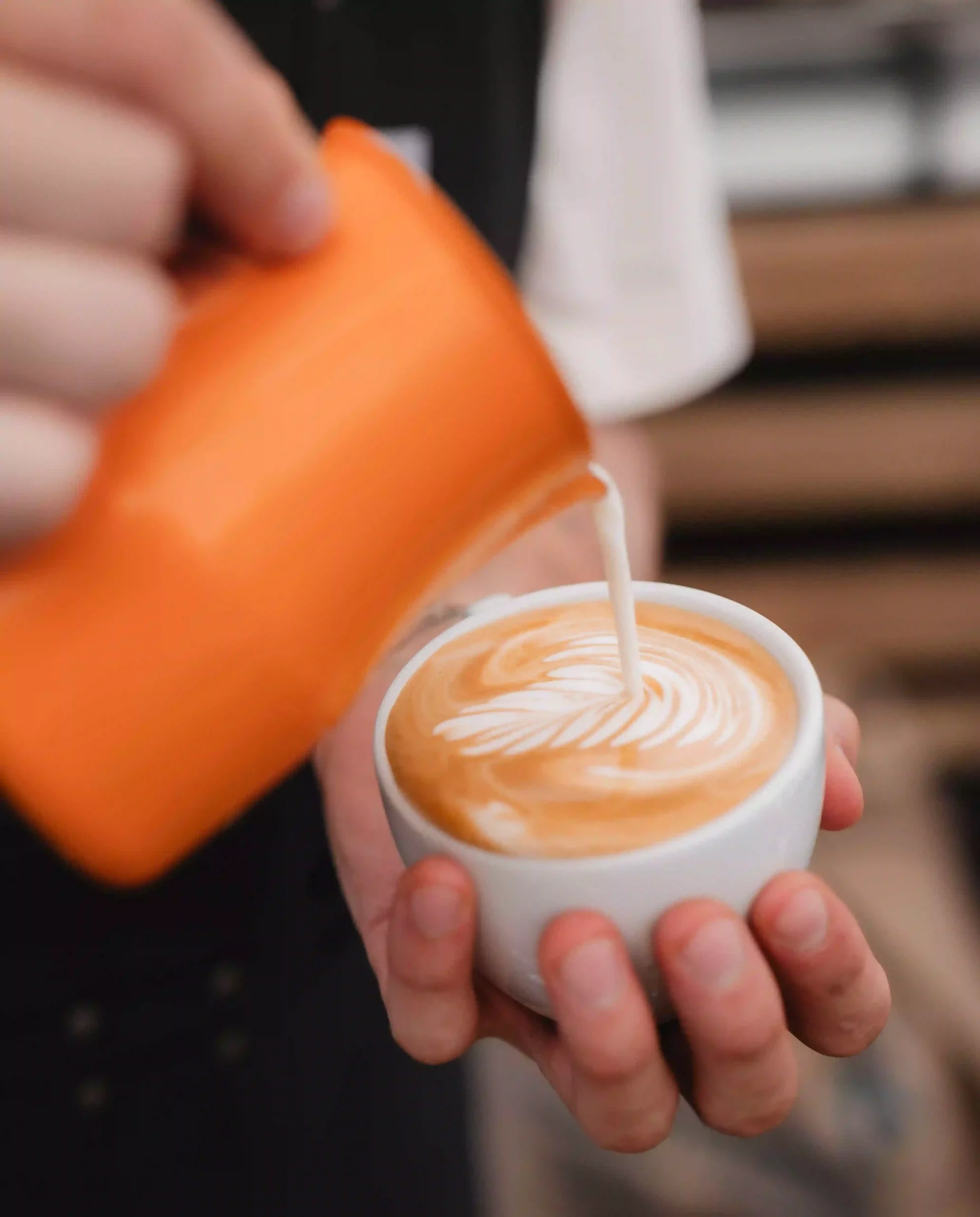 Barista macht Latte Art mit einem Cappuccino